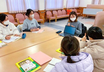 介護施設でのレクリエーション活動。入居者と職員が一堂に集まり、ゲームやプログラムに参加している風景。